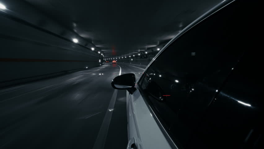 High-speed cinematic drive through modern urban tunnel filmed from locked-down car exterior at night