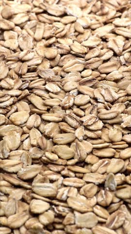 Uncooked oat flakes background. Raw oatmeal porridge ingredient. Healthy breakfast and diet concepts, vertical video