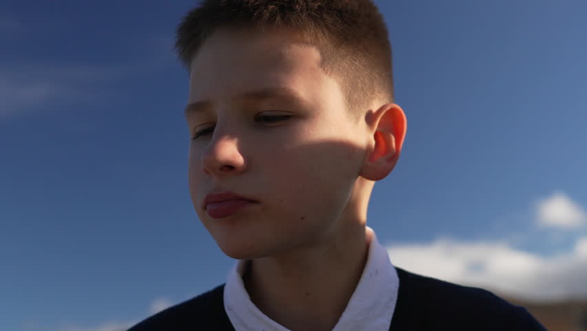 Teenager, eating, snacks. Close up of a hungry young boy enjoying a quick chip outside under the bright summer sky.