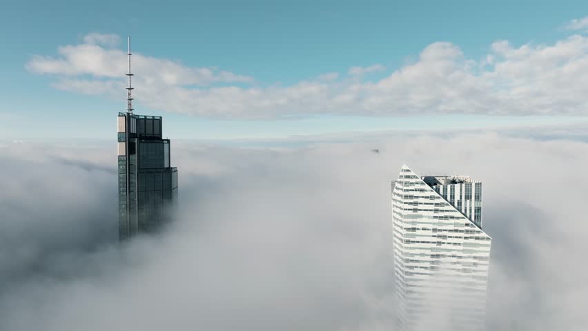 Skyscrapers above low clouds in foggy Warsaw. Aerial drone footage of modern skyscrapers in central Warsaw rising above low clouds and dense morning fog.