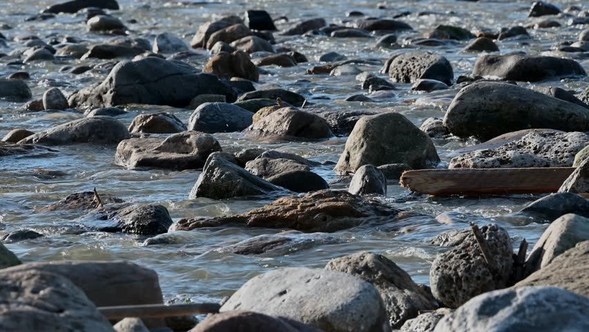 Shallow coastal water flowing over rocks on the shoreline in Ericeira, Portugal. Moving water, textured stones and natural coastal scenery