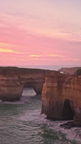 Sunset over the ocean, with large flock of mutton birds circling over the island in focus, Great Ocean Road, Port Campbell, Victoria, Australia