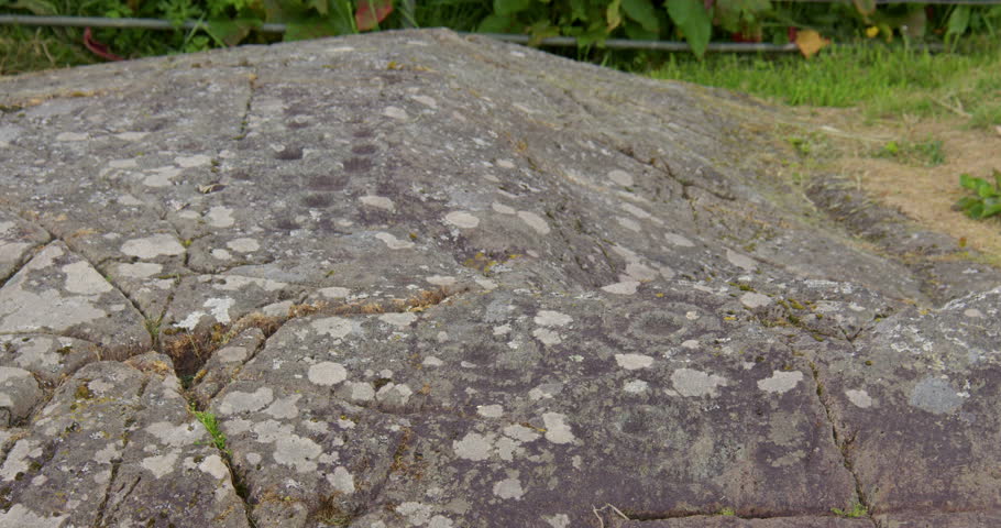 Slow zoom in of Baluachraig cup and ring carving in natural outcrop of level rock at Kilmartin glen