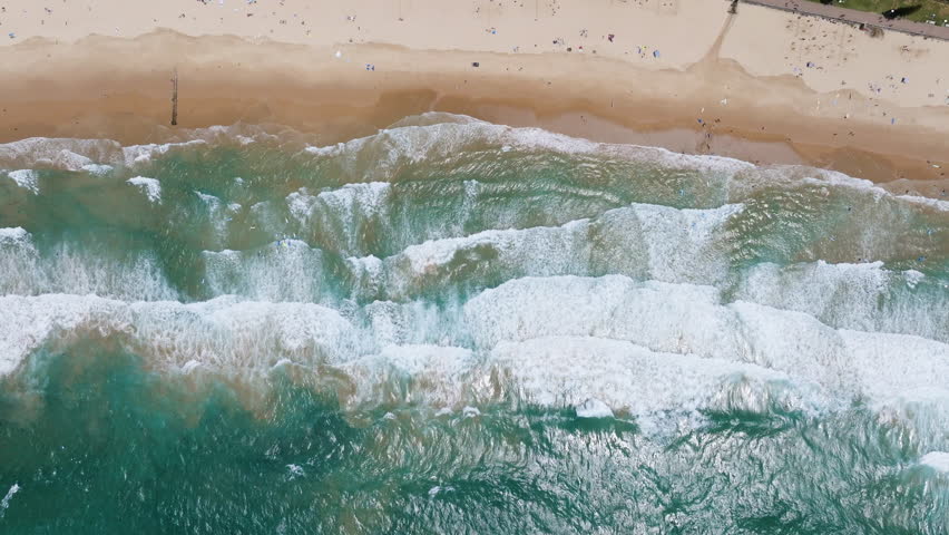 Top down drone shot above waves at the Manly Beach, in sunny Sydney, Australia