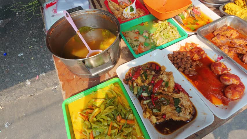 Handheld close-up panning shot of Indonesian street food in Jakarta, revealing a variety of traditional dishes, rich sauces, and vibrant flavours served fresh at a local street market in Indonesia