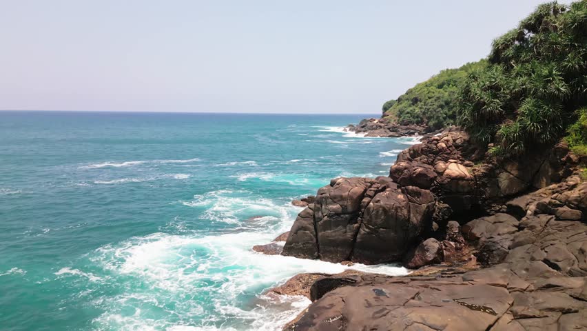Aerial Fly over of Rocky Seashore, South Coast of Sri Lanka. Cinematic view rugged rocky shoreline. Sri Lanka southern coast, waves crash against cliffs.Turquoise ocean meets dramatic coastal terrain
