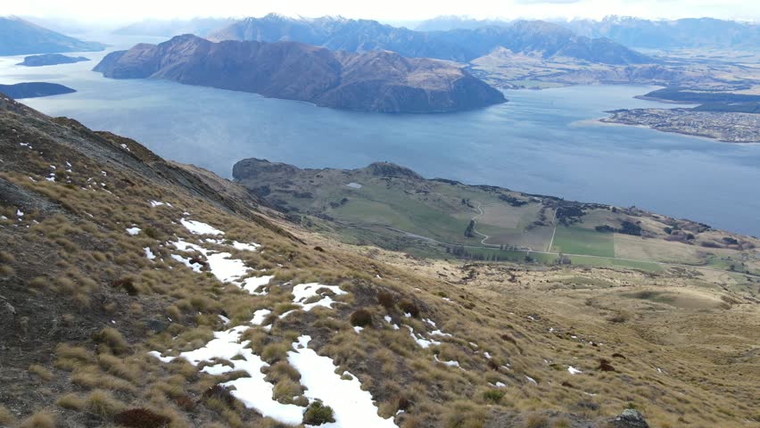 Aerial forward push view of Lake Wanaka and mountains from Roys Peak, South Island, New Zealand