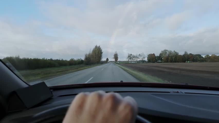 Muted colors countryside highway drive with distant rainbow and calm tension