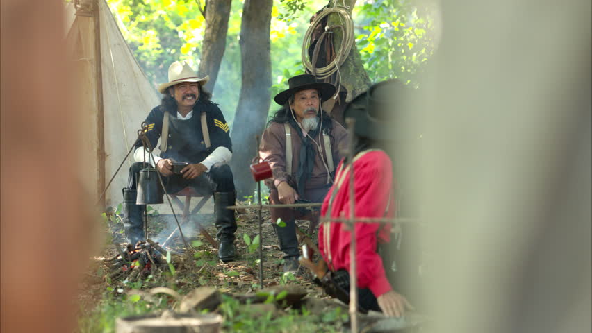 Cowboys preparing food at a campfire, roasting meat together in a warm and rustic outdoor setting