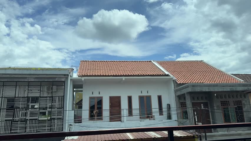 Time lapse of cloudy sky above residential houses on a sunny day with diverse architecture. Time-lapse clouds video
