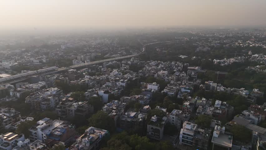 Elevated metro lines glide over South Delhi’s green canopy at Nehru Enclave, framed by commercial towers and dense neighborhoods, highlighting the city’s evolving skyline.