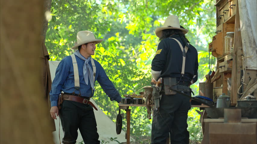 Cowboys gather around a chuck wagon preparing fresh ingredients for cooking