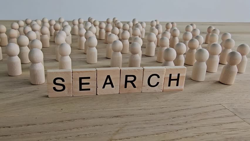 Crowd of wooden figures gathered around the word search on a wooden surface