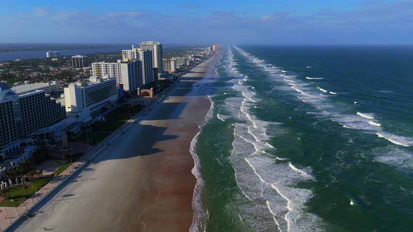 Drone shot over Daytona Beach Florida from sandy shore to ocean waves