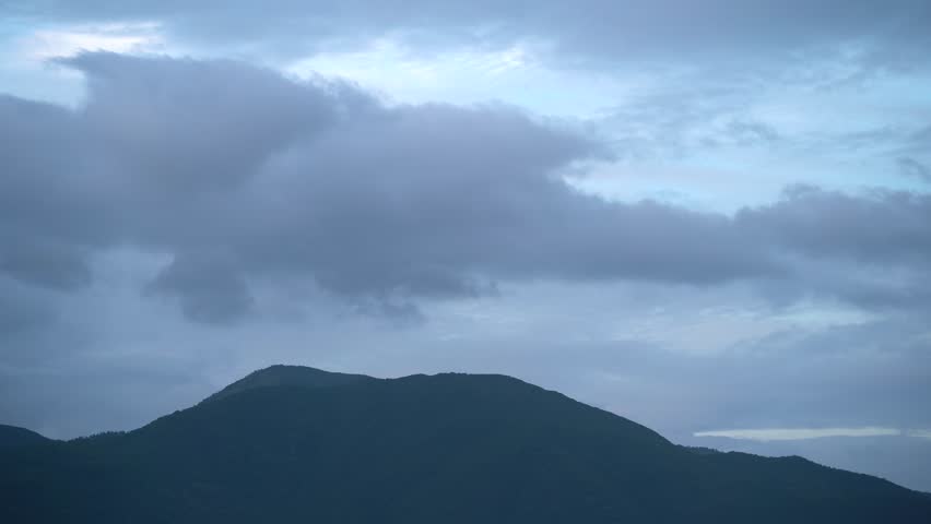 A large hill at dusk against a sky with clouds