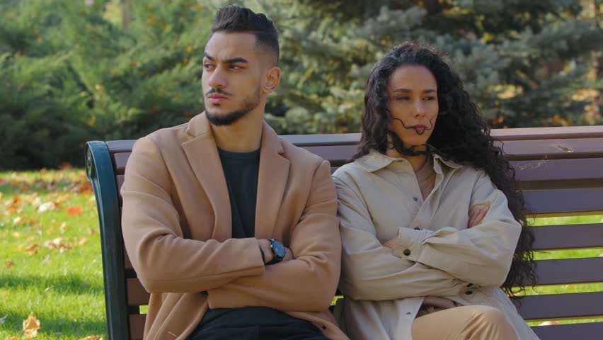 Stressed hispanic couple ignoring feeling offended on bench in autumn park negative family silent ignore separation Arabian man with Caucasian woman dating failure in city quarrel breakup divorce