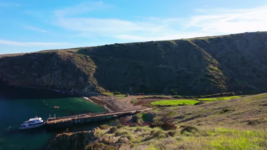 Clear turquoise waters and pebble beach of Scorpion Anchorage nestled between the dramatic volcanic cliffs of Santa Cruz Island