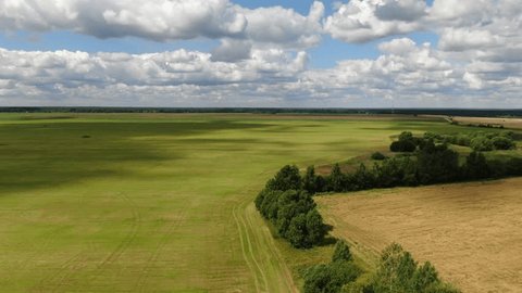 Aerial Flight Over Green Fields with Drifting Clouds