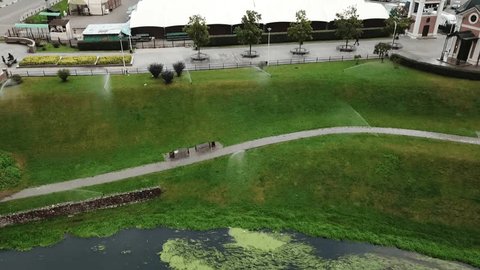 Drone Revealing Park Irrigation beside Urban River