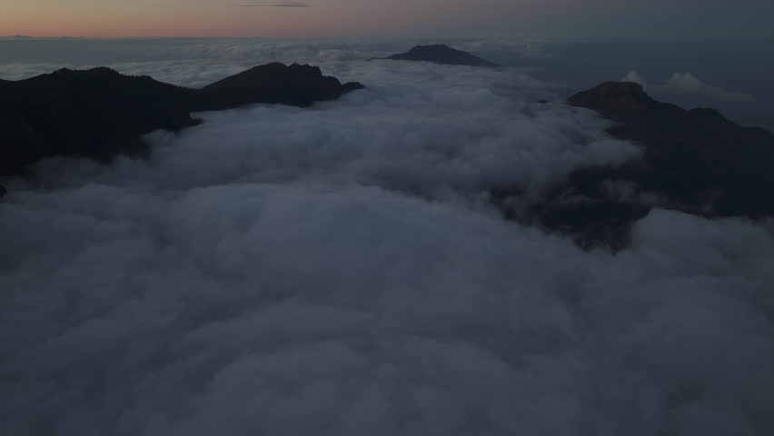 Majestic aerial view of the Caldera de Taburiente in La Palma flying above the clouds at sunrise