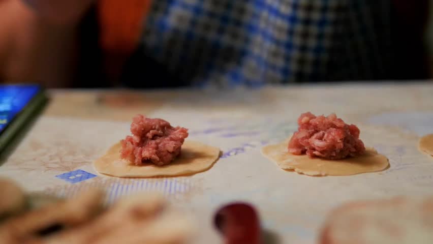 Close-up of Hands Folding Traditional Handmade Meat Dumplings on a Floured Surface