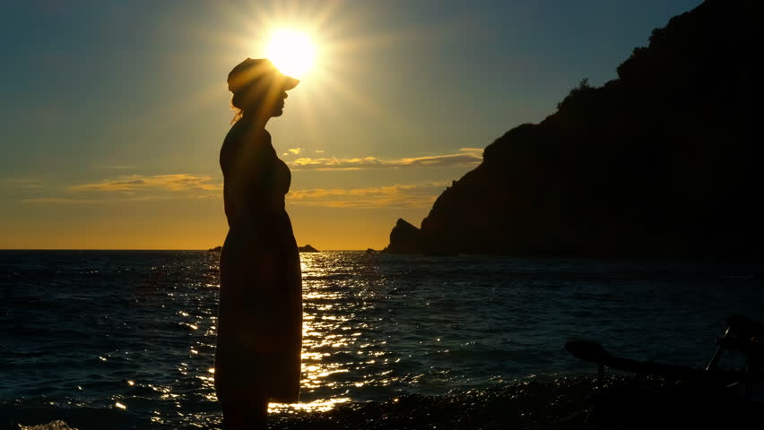 Silhouette of a woman watching a beautiful sunset on the beach. Beautiful woman