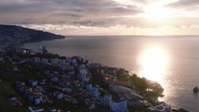 Aerial view of Funchal, Madeira, Portugal shows red roofs, clustered resorts, a cruise ship at the harbor, steep cliffs, and a circular rooftop as the camera drifts at golden hour. - Powered by Shutterstock - Get 15% off with code: PIKWIZARD15