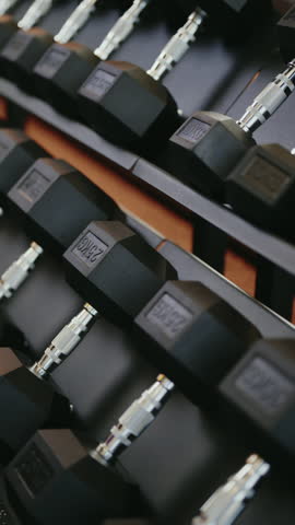 Close-up of dumbbells arranged on a rack in a gym. This signifies fitness, strength training, and a healthy lifestyle. The focus is on the weights, suggesting a workout routine.