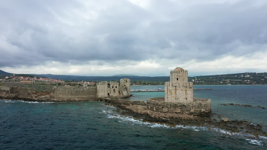 Historic Methoni Castle stands on the rocky coastline with dramatic clouds overhead and turquoise sea surrounding its ancient stone walls in Greece.