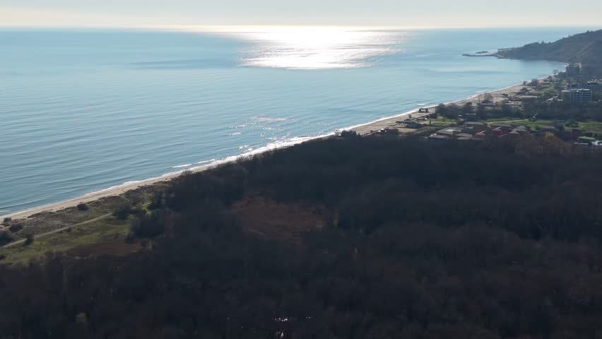 Aerial view of coastal city and blue sea, urban shoreline, calm weather, distant horizon, travel destination, seaside landscape.