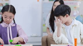 Two elementary students solve math problems with counting blocks as teacher guides attentively - Powered by Shutterstock - Get 15% off with code: PIKWIZARD15