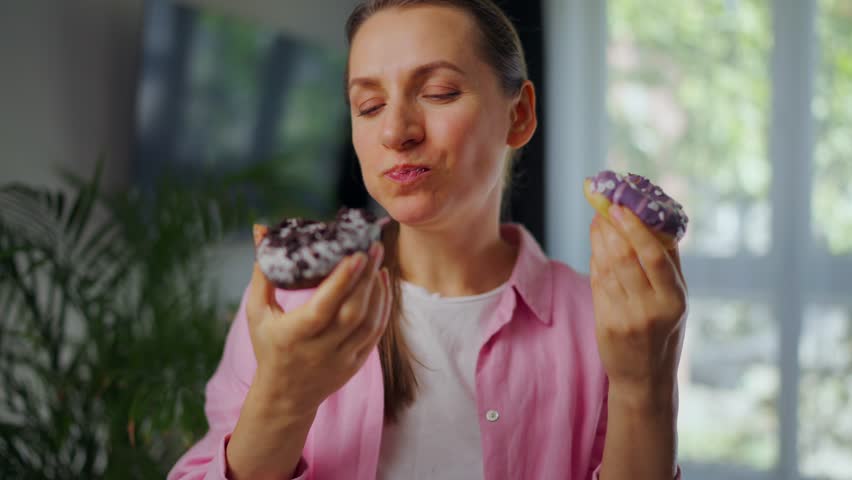 Woman with eating disorder eating two donuts with pleasure and at the same time