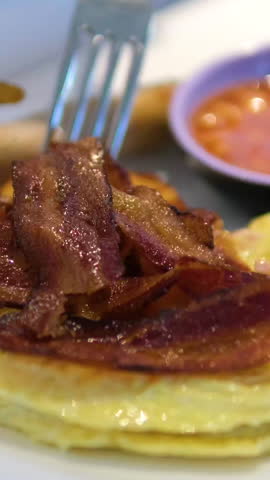 Bacon omelette tomato Cutting into a fluffy omelette on a plate