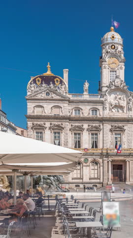 Hyperlapse of Hotel de Ville de Lyon, the historic city hall of Lyon, France. People stroll near the fountain on the square timelapse. A baroque and classical architectural marvel under a blue sky