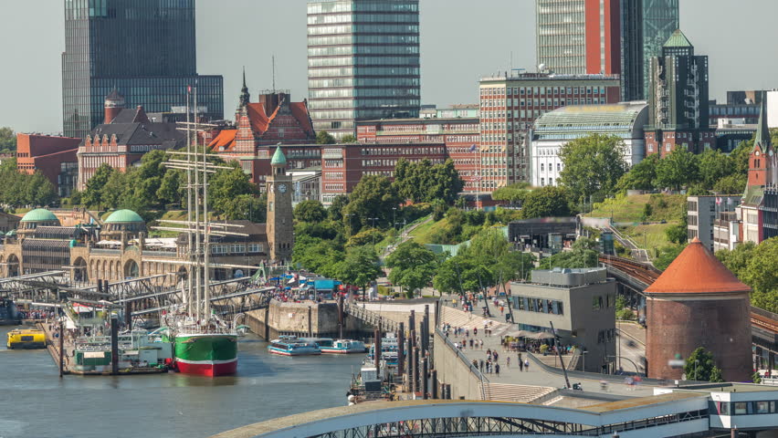 Jan Fedder Promenade aerial timelapse in Hamburg, Germany, a vibrant waterfront area. Ships and boats on the Elbe River with famous buildings in background. Relaxation and scenic beauty