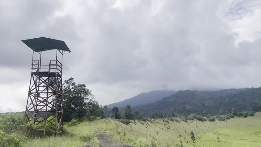 Observation Tower on Grassland Hill Under Cloudy Sky