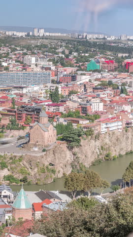 City panorama with Metekhi Virgin Mary Assumption Church aerial timelapse and the Statue of King Vakhtang Gorgasali above the Kura River. Traffic on a street and historic buildings. Tbilisi, Georgia.