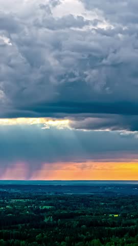 Vertical time-lapse showing fast-moving storm clouds over a rural landscape, with fading sunset light on the horizon as night approaches.