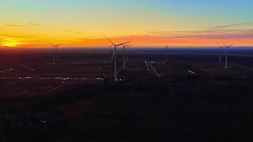 Wide drone aerial of a wind farm at sunset, turbines over farmland under an orange-to-blue sky gradient and soft haze—cinematic renewable power backdrop. - Powered by Shutterstock - Get 15% off with code: PIKWIZARD15
