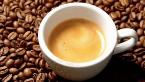 Close up view of hot espresso coffee with crema in white cup atop rich brown coffee beans - Powered by Shutterstock - Get 15% off with code: PIKWIZARD15