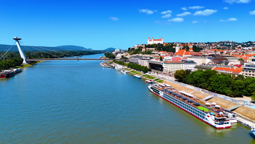 Beautiful bright scenery of old city in Bratislava, Slovakia. Drone footage above the waterscape of the Danube River.