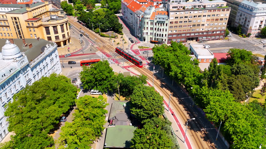 Following the tram moving by the road in the city center of Bratislava, Slovakia. Drone footage over the sunny cityscape.