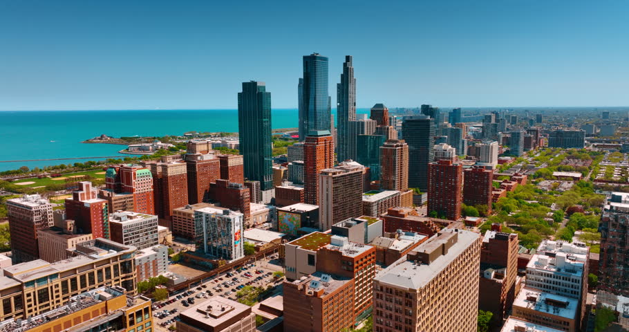Three skyscrapers standing out from the scenery of Chicago, Illinois, USA. Panorama of metropolis at the backdrop of blue waterscape. Aerial view.