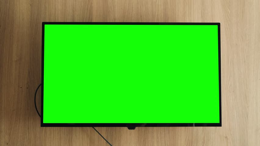 Smart LCD TV screen with green screen on wooden wall background in the living room. Chroma key screen for advertising. High quality 4k footage