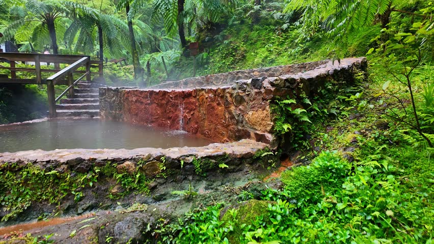 Caldeira Velha hot springs with thermal water pools in lush tropical forest on Sao Miguel Island, Azores, Portugal, slow-motion revealing steadicam footage of this geothermal site.