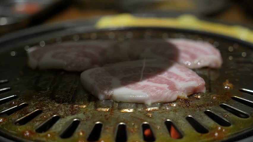 Grilled meat on a charcoal grill pan at Korean BBQ restaurant.