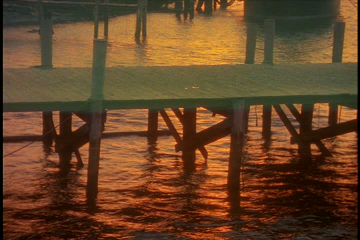 Exterior shots of seaport village in early morning light in Connecticut; CU small dock at sunrise, orange light reflected on surface of water.