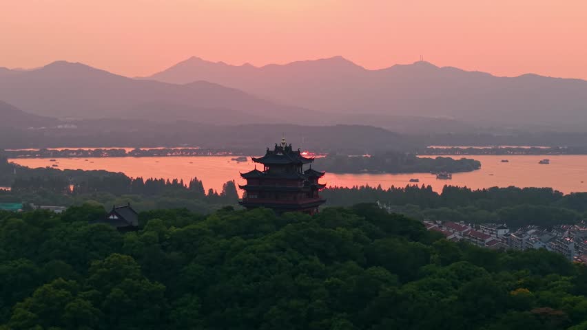 Aerial view of Chenghuang pagoda at sunset over Xihu lake in Hangzhou featuring mountains and lush green trees