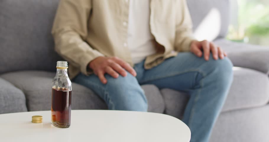 Man refuses alcohol drink, choosing sobriety and health. He raises a palm to the glass and bottle, signaling refusal, danger, and support for recovery. Refusal today prevents future addiction.