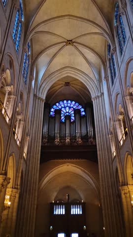 The grand organ under a vibrant rose window inside the stunning Notre-Dame Cathedral in Paris. Soaring vaulted ceilings and intricate stained glass bathe the stone architecture in ethereal light